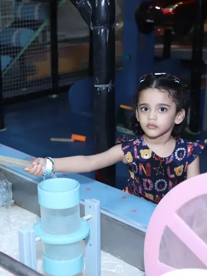 A toddler is fascinated by the mechanics of our water and pellet wheel play station.