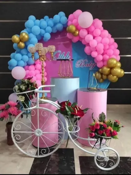 A sweet and simple baby shower setup with a pink and blue theme. The decorative bicycle filled with flowers adds a unique and charming touch.
