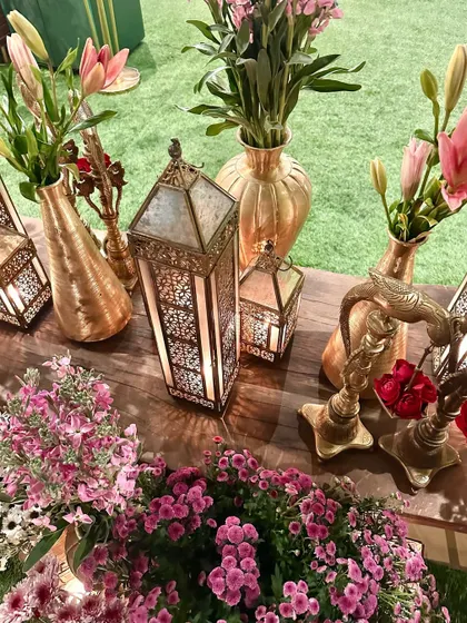 More details of our brass decor, including vases, lanterns, and candle holders, mixed with pink and white flowers.