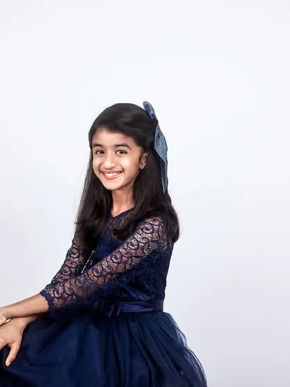 A beautiful, classic portrait of a young girl in a blue dress, taken against a clean white studio background for a timeless look.