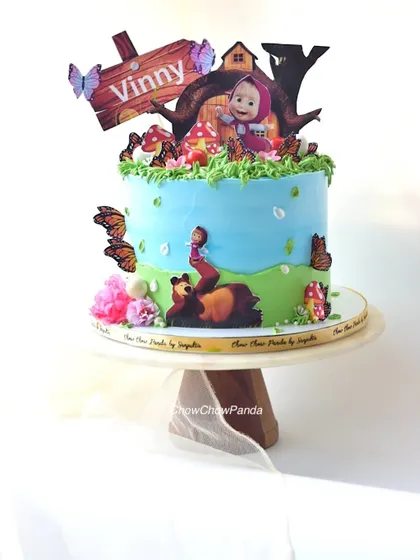 A cake based on the cartoon Masha and the Bear. This Chocolate Orange cake features a woodland scene with the characters, butterflies, and mushrooms.