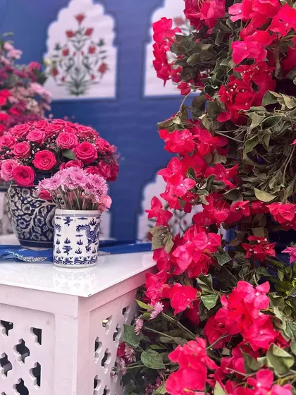 A beautiful Mehendi setup with a blue and pink color scheme, featuring traditional Indian motifs, bougainvillea flowers, and elegant seating.