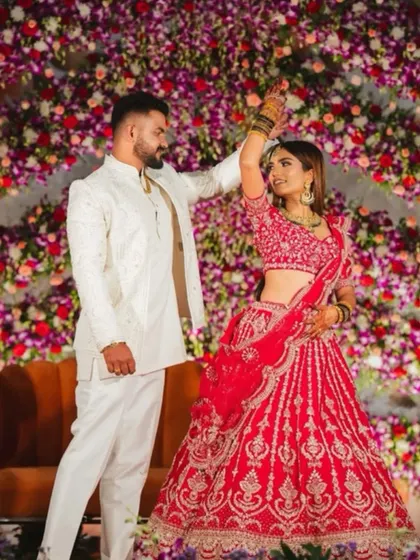 A candid moment of a couple dancing at their reception. The backdrop is a stunning wall of purple and pink orchids, adding to the festive and romantic mood.