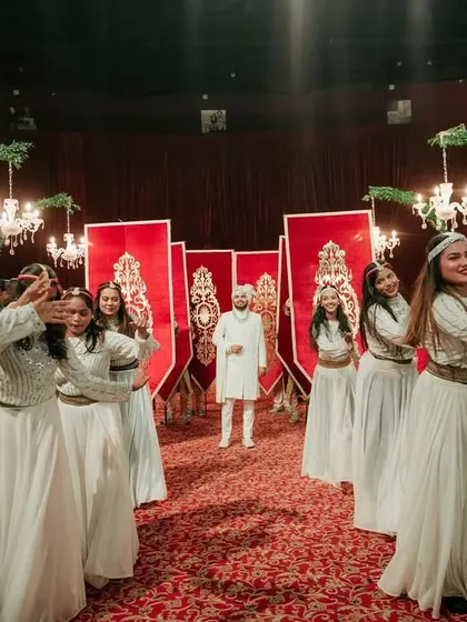 The groom's arrival, marked by tradition and excitement. He is welcomed by a troupe of dancers in white, creating a beautiful and coordinated entry sequence.
