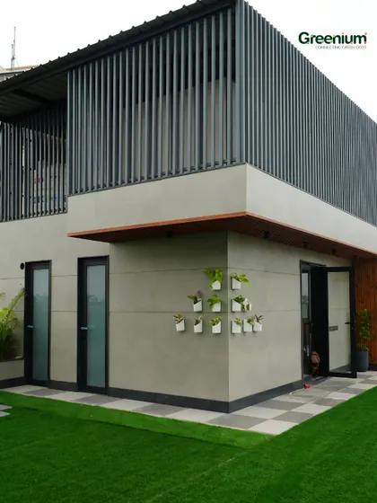 The "after" shot of the Gurgaon terrace transformation. I covered the mumty with a sleek grill design, added charming wall planters, and laid down lush green grass to completely change the look and feel.