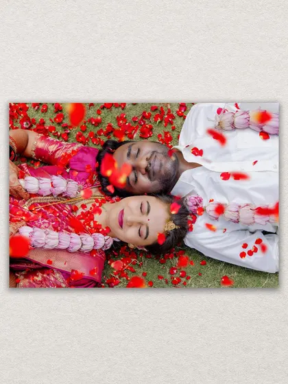 A creative overhead shot of the bride and groom lying on the grass, showered with red rose petals after their ceremony. A truly romantic final shot.
