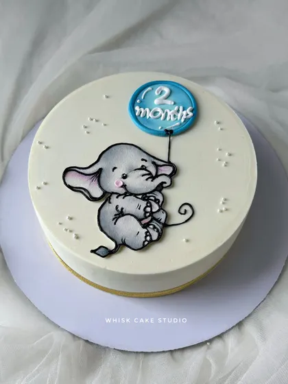 A cute and simple cake for a monthly birthday celebration. This design features a hand-painted baby elephant holding a balloon.