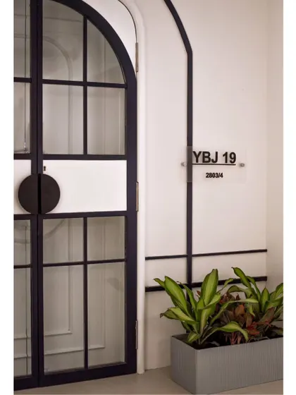 The journey begins before you even step inside. The entrance to the 'YBJ Residence' features a custom arched door with glass panels, hinting at the timeless blend of modern and classic charm within.