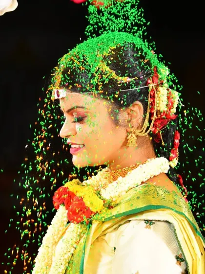 A joyful moment from a Muhurtham ceremony. The bride's profile shows her elegant hairstyle and makeup that holds up beautifully, even during the most active parts of the wedding rituals.