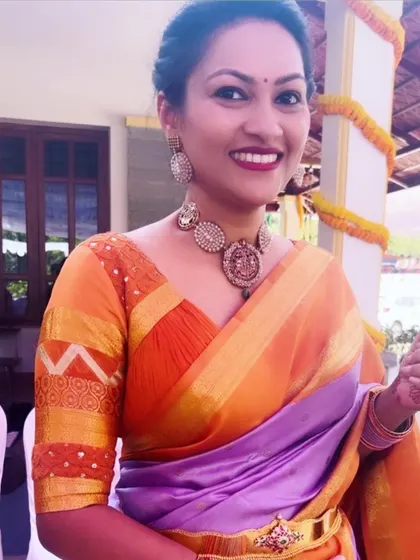 A client in a purple and orange silk saree. Her custom orange blouse features a unique design on the sleeves, blending traditional patterns with a modern cut.