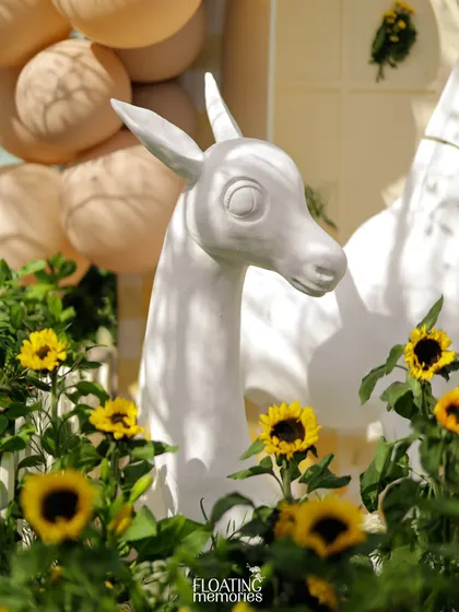 A close-up of a gentle deer prop surrounded by a field of sunflowers, creating a soft and whimsical moment within the safari theme.