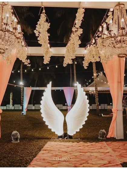 A stunning photo opportunity with large, illuminated angel wings set against the backdrop of the reception lawn.