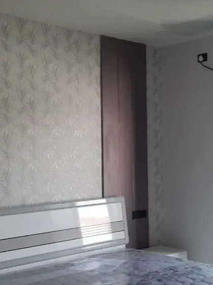 A snapshot from a successfully handed-over project, this bedroom features textured wallpaper and a simple, modern headboard. The large window allows for ample natural light, creating a bright and pleasant space.