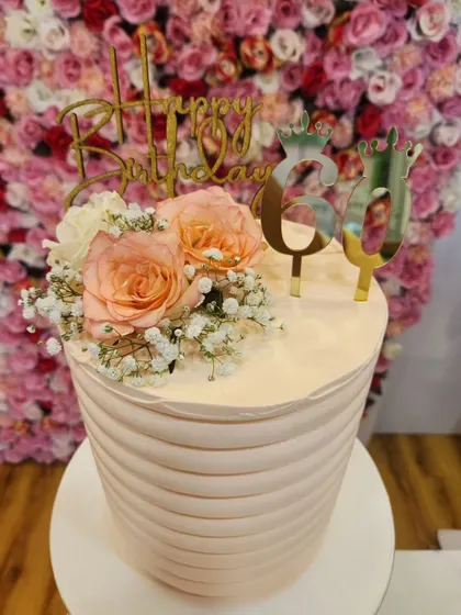 A still image of the elegant tall cake for a 60th birthday, showing the clean lines and the beautiful floral topper.