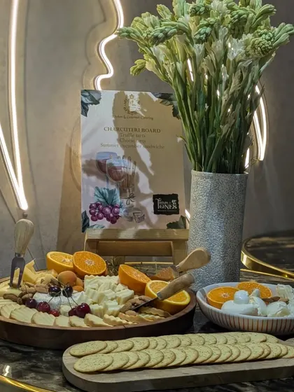 An elegant cheese and cracker display set against a neon-lit wall. This setup for Trims and Tones salon combines modern aesthetics with classic gourmet offerings.