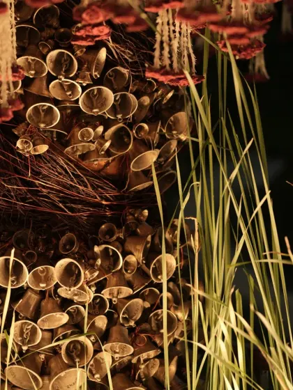An evening shot capturing the warm light on the brass bells, with the hanging floral canopy above.