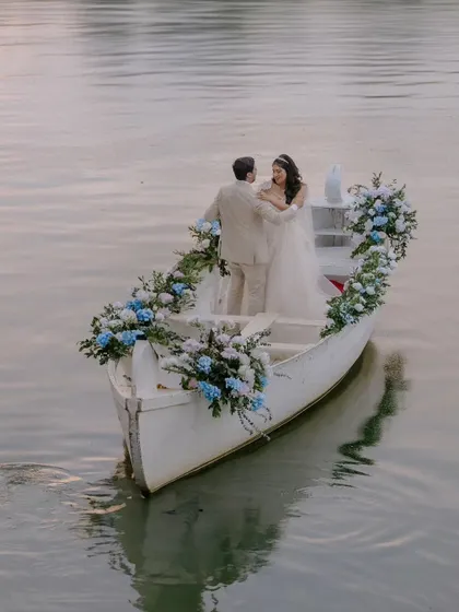 A romantic escape. The couple shares a quiet moment in a beautifully decorated boat, waving to their loved ones as they begin their journey together.