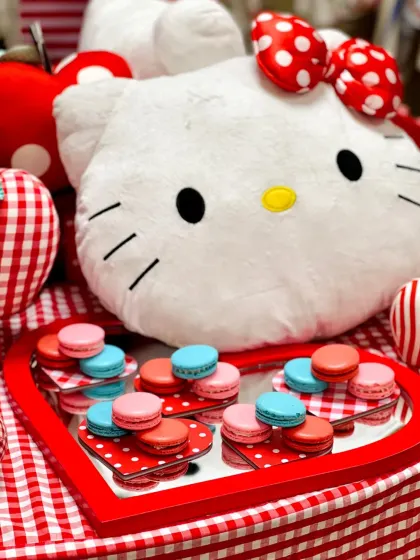 Colorful macarons displayed on a heart-shaped tray next to a Hello Kitty plush, perfectly capturing the "kawaii" theme of the event.