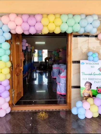The welcoming entrance to the Cocomelon party, with a pastel rainbow balloon arch and a personalized welcome sign.