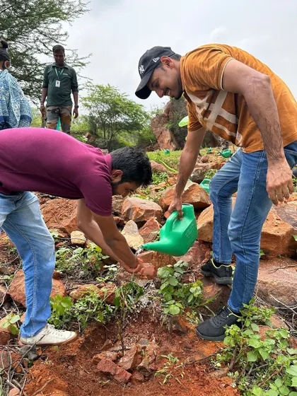 Teamwork makes the dream work as Beumer Group employees help each other water a newly planted sapling on the rocky slopes of the forest.