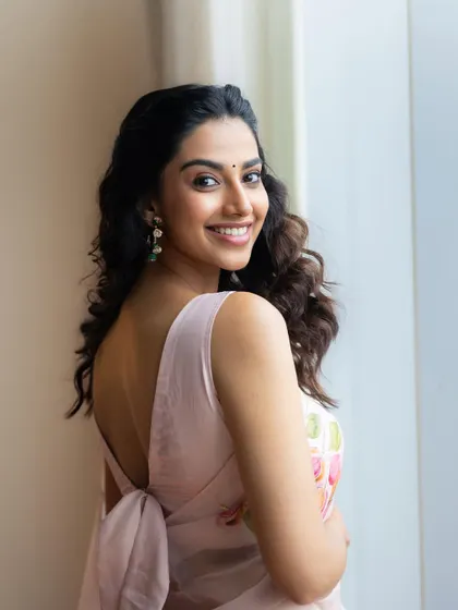 A lovely over-the-shoulder shot from the pink floral saree look. This angle highlights the beautiful back detail of the blouse and the model's soft, natural hair and makeup.