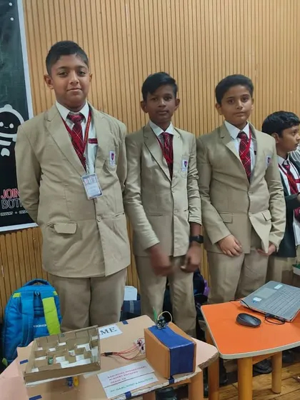 Students stand by their project displays at the Robozest 2.0 event, ready to explain their work to judges and visitors.