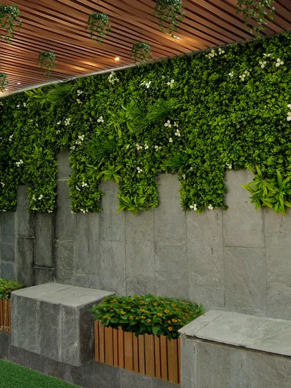 A vertical garden can completely change a space. Here, I used a combination of artificial greenery with small white flowers to cover a stone wall, creating a lush, maintenance-free feature that adds life and style under a slatted ceiling.