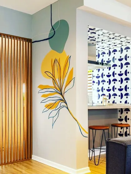 This wall features a modern, abstract mural with organic shapes and a curated colour palette. It shows how wall art can complement other design elements, like the patterned partition, to create a cohesive and artistic interior.