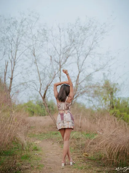 This pose, with arms raised, creates elegant lines and a sense of freedom. It's a classic modeling pose that works beautifully against the stark, natural background of the trees.