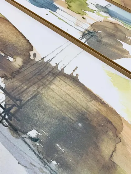 A detailed view of the "Dusty Splash" abstract artwork, showing the subtle texture of the paper and the delicate lines within the watercolor, all protected behind glass in a minimal metal frame.