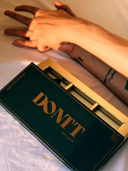 An artistic, top-down shot that combines the product with a human element. The focus on the hands and the empty box tells a story of indulgence.