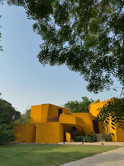 Framed by the leaves of a neem tree, the building feels like a natural extension of the surrounding landscape.