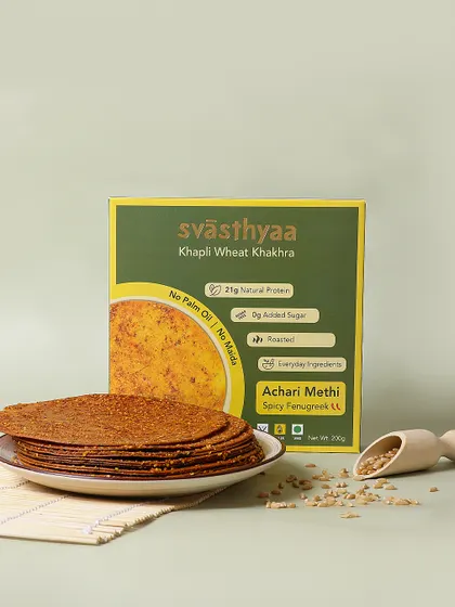 A simple and clean product shot for Achari Methi Khakhra. The focus is on the product's texture and the packaging's health claims, appealing to health conscious consumers.