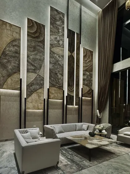 A different perspective of this contemporary living room, showing how the interplay of light and shadow transforms the space at night. The strategic lighting highlights the textures of the wall panels and the sheen of the marble floor, creating a sophisticated and dramatic ambiance.