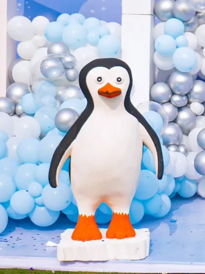 An adorable penguin prop stands in front of a cascade of blue and white balloons, adding a playful touch to the winter theme.