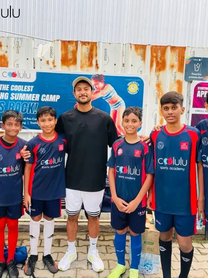 Our young football team poses with a coach. The team wears official Coolulu sports academy jerseys, ready to represent us on the field.