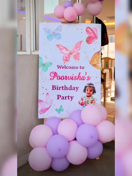 A welcome sign for Poorvisha's butterfly-themed birthday party. The sign features a photo of the birthday girl, making it extra personal.