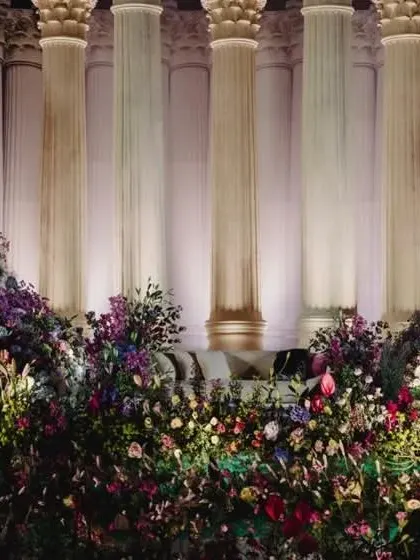 A close-up of the overflowing flowers that cascade down from the Roman pillar backdrop, blending soft and jewel tones for a dramatic effect.