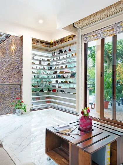 This informal living space is designed around light and views. A custom corner shelving unit displays the client's collection, while a stone-clad wall and MS grill skylight add texture and architectural interest.