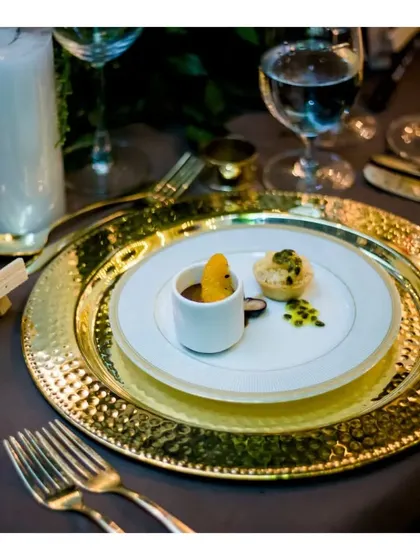 An example of our plated dessert course, featuring a Burnt Orange Chocolate Cremeux and a passion fruit tartlet on a hammered gold charger plate.