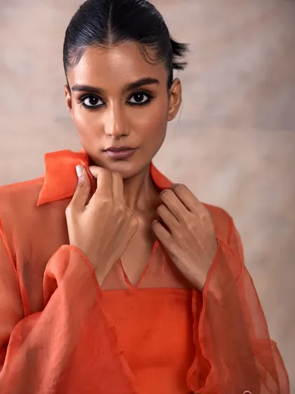 This look for Akashi Clothing features a warm, monochromatic orange outfit. The makeup is kept bronzed and sun-kissed, with a soft smokey eye to add definition.
