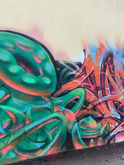 A full view of the 'bijli flow' piece, showing the contrast between the cool green bio-mechanical forms and the hot orange and pink lettering.