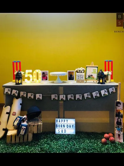 We hit it for a six with this custom cricket theme for a state cricketer's 50th birthday. The decor features a personalized 'Happy Born Day' lightbox, marquee numbers, and authentic cricket gear like pads, a helmet, and a custom photo bat to celebrate his passion.