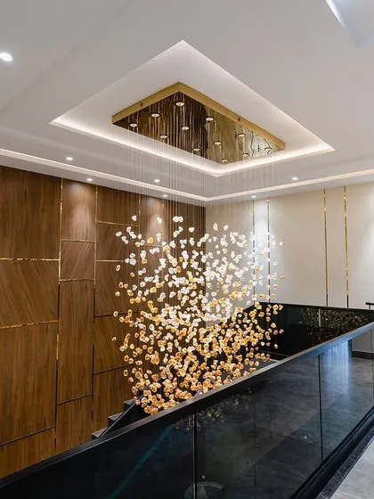 This concept showcases a spectacular custom hanging light fixture that cascades down the stairwell, creating a dramatic and luxurious focal point.