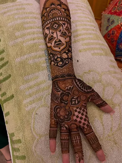 The complete arm and hand design, showing how the bell motif arm band connects to the intricate patterns on the palm.