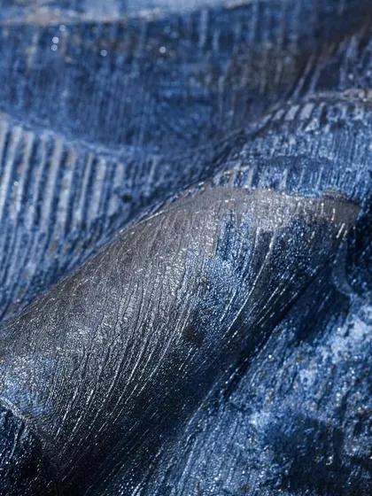 A close-up of a deep blue wallpaper with a heavily textured, almost metallic finish. This design adds incredible depth and a touch of drama, perfect for an accent wall or a moody, luxurious space.