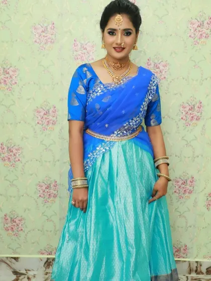 A full-length still image of the blue and aqua half saree, showing the complete outfit with the waist belt (vaddanam).