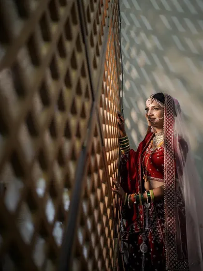 An artistic bridal portrait using shadows and light. The bride stands by a latticed wall, creating a dramatic and beautiful play of light on her.