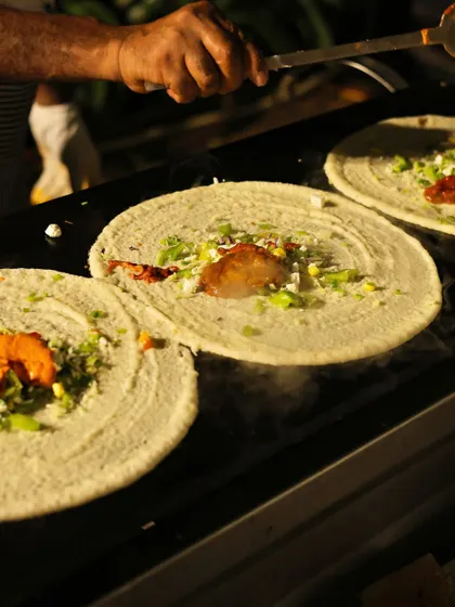 A chef at my live dosa station expertly prepares multiple dosas at once. This action shot shows the steam rising as fresh toppings are added to the crispy crepes.