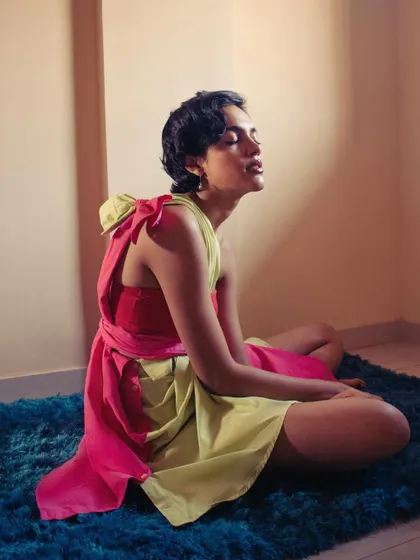A quiet, sunlit portrait from an experimental series. The model sits peacefully in a dress fashioned from two shirts, showcasing creative, spontaneous styling.